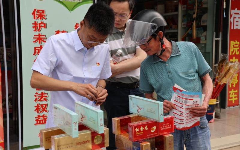 工作人员在普法宣传台前向消费者介绍真假烟识别方法。