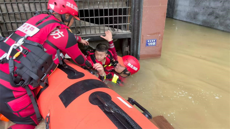 7月1日，咸丰县高乐山镇廖家塘巷，恩施市施州大道消防救援站战斗班副班长何磊和队友解救被困孩子。徐朋伟摄